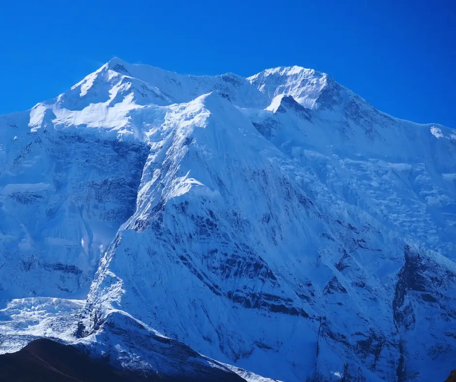 view of massive mountain under blue sky in upper pisang at Annapurna Circuit Trek