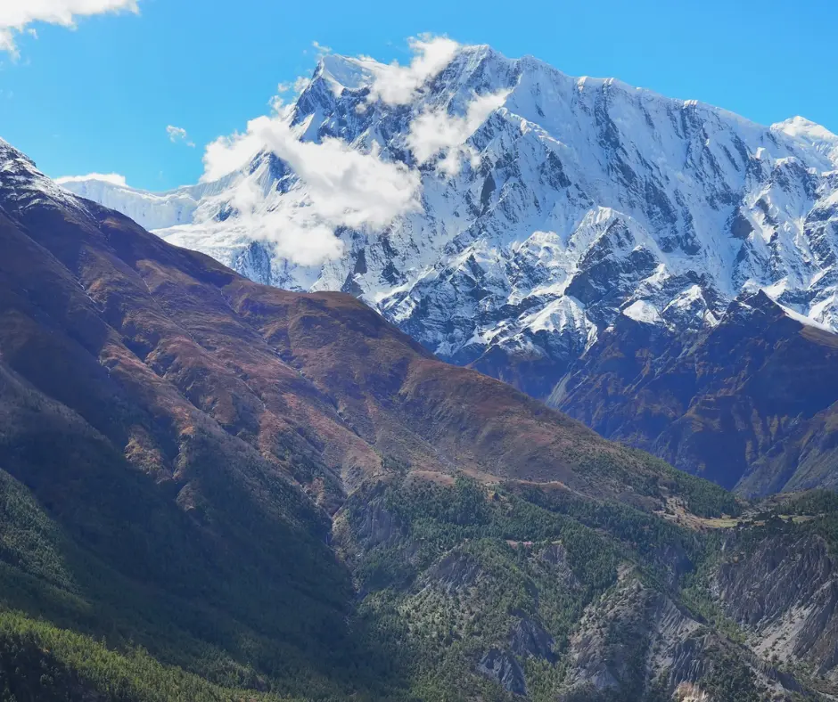 green landscape with mountain in the background at Nar Phu Valley Trekking